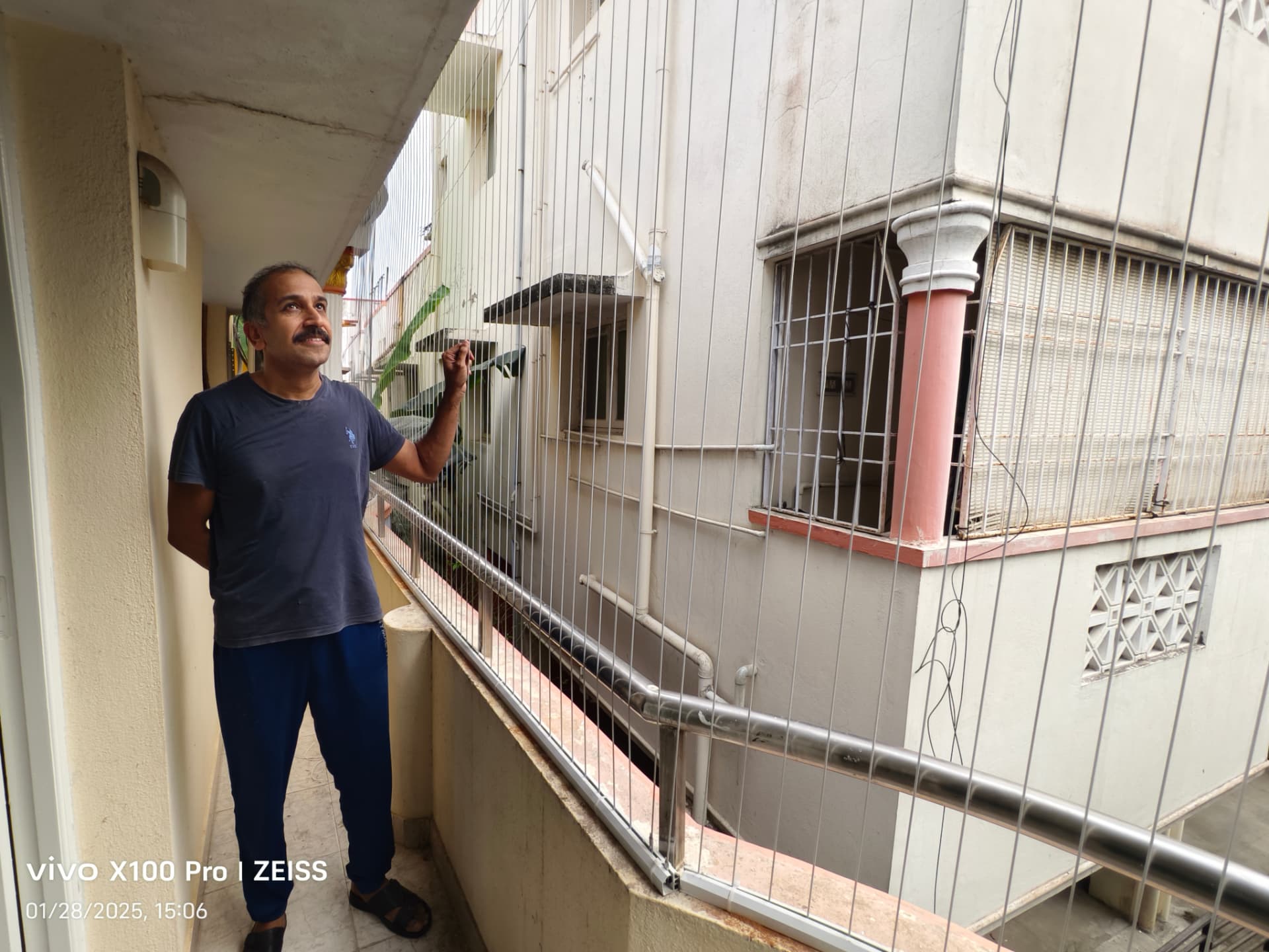 Customer inspecting newly installed vertical invisible grill cables on an apartment corridor balcony
